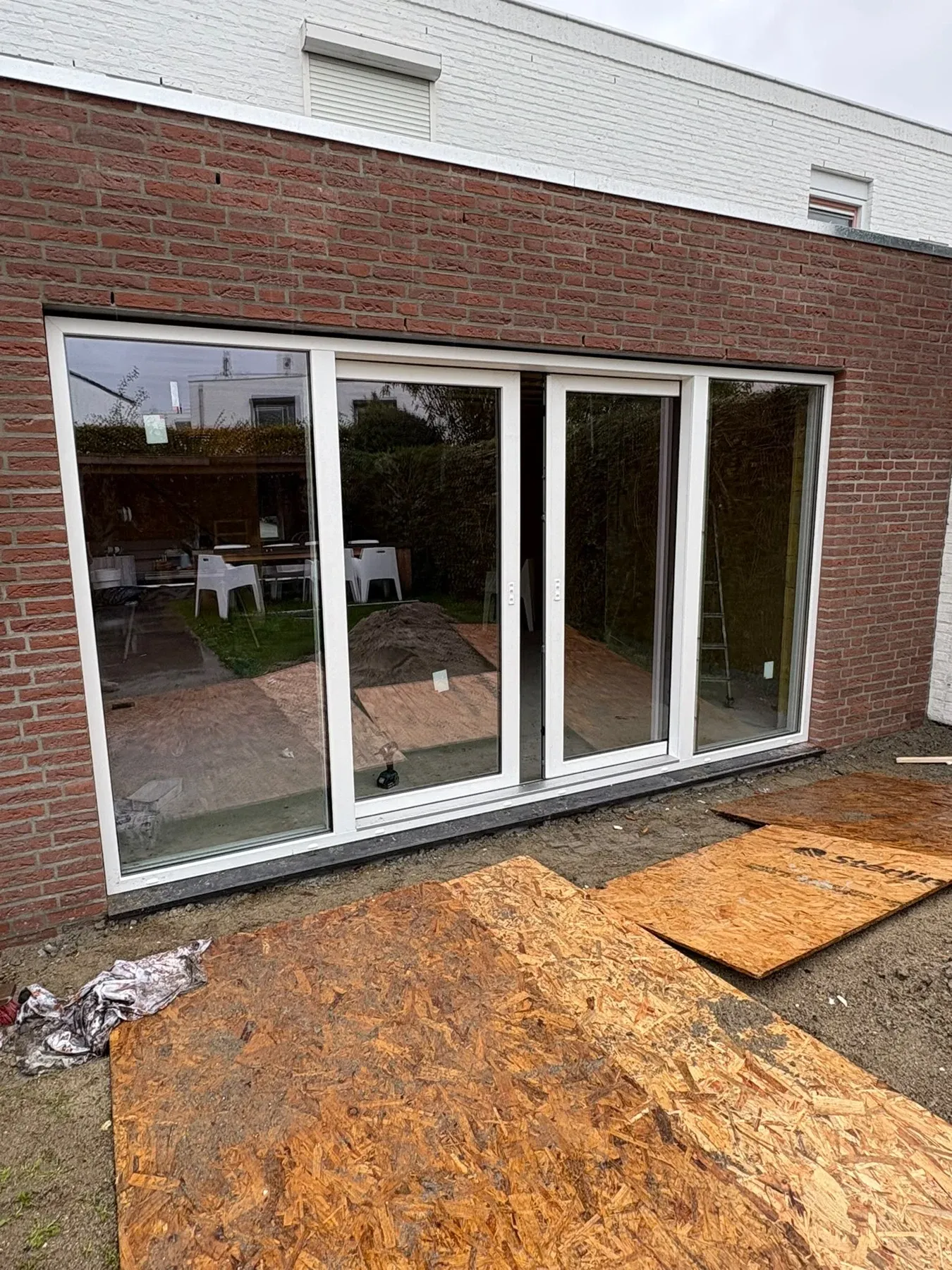 Witte deuren en glaspartijen in een gemetselde achtergevel